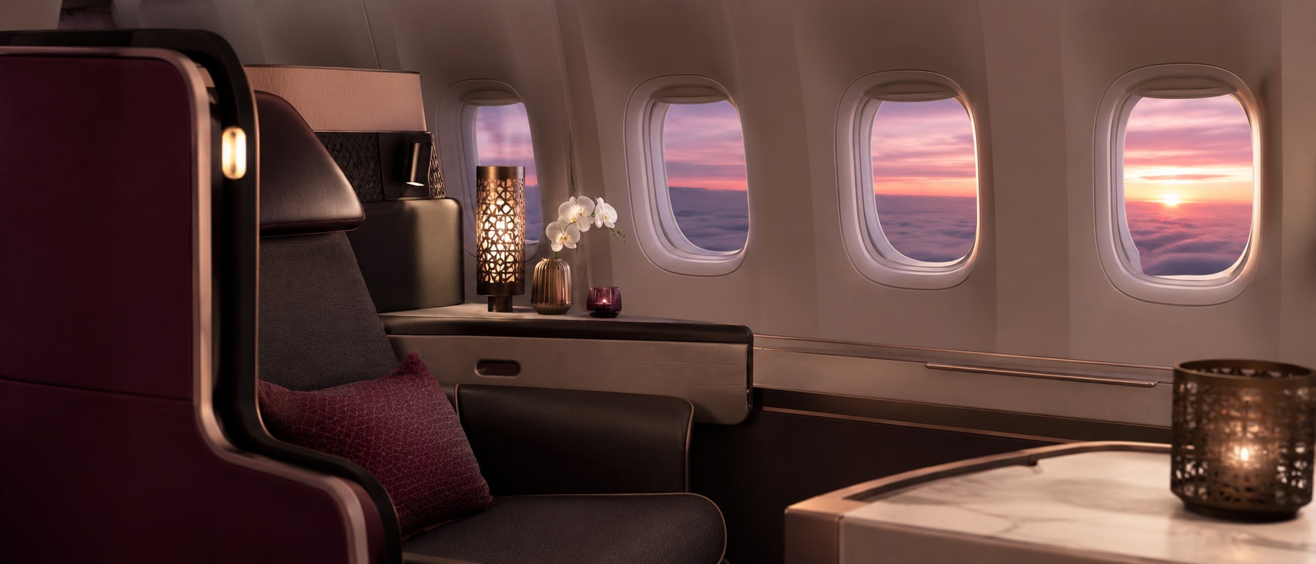 Premium aircraft cabin suite with warm lighting and a sunset sea of clouds through the windows